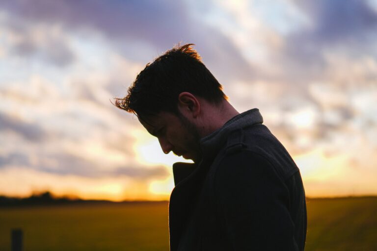 A dimly lit man slightly hunched over