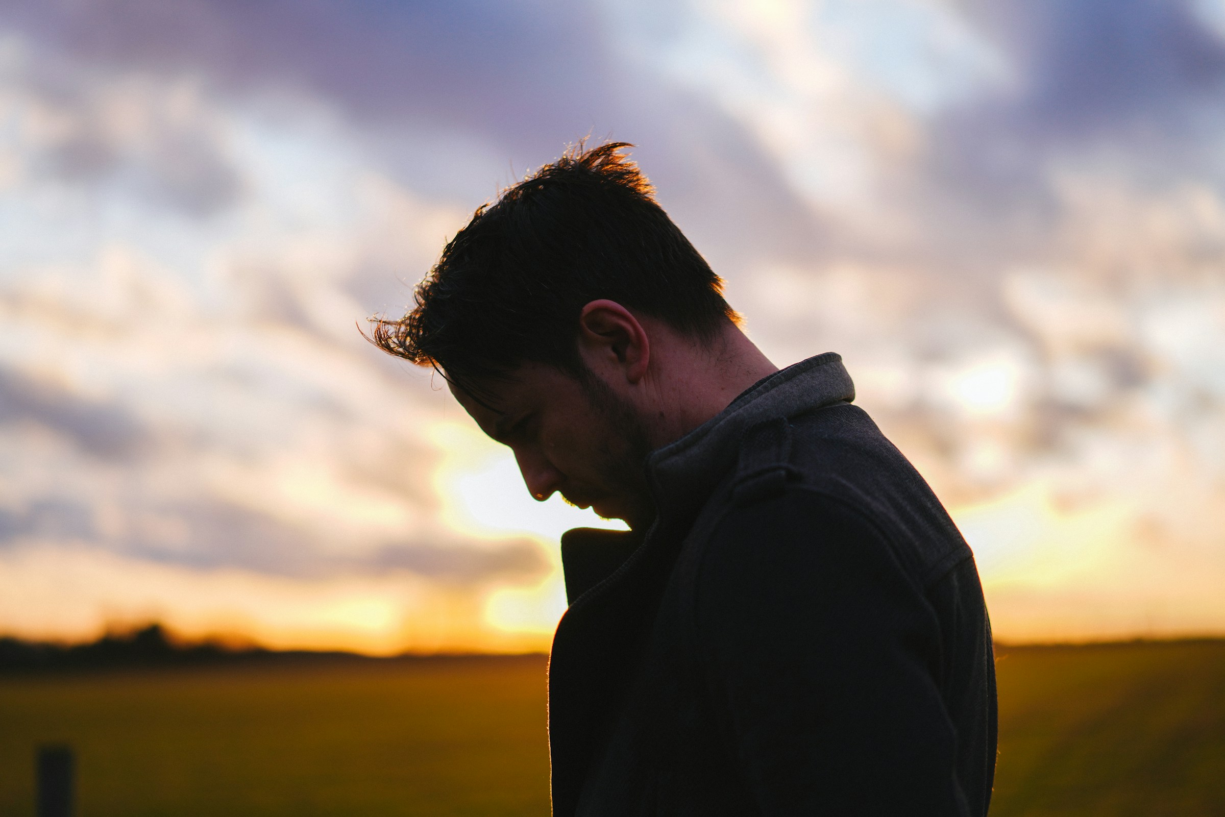 A dimly lit man slightly hunched over